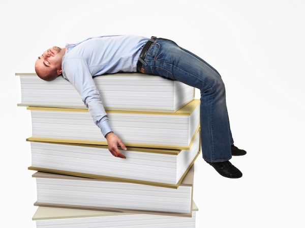 portrait of stressed man sleeping on a 3d book pile